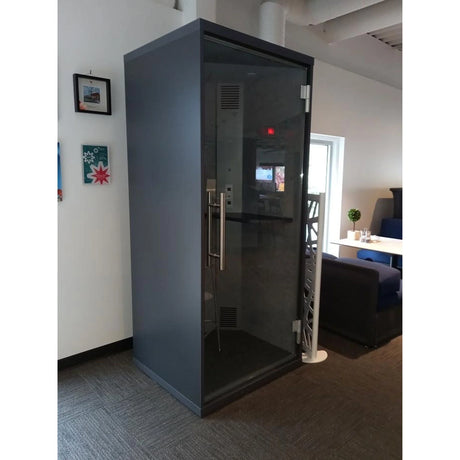 Cabine acoustique OneZone noire installée dans un bureau moderne avec cloison vitrée et éclairage naturel