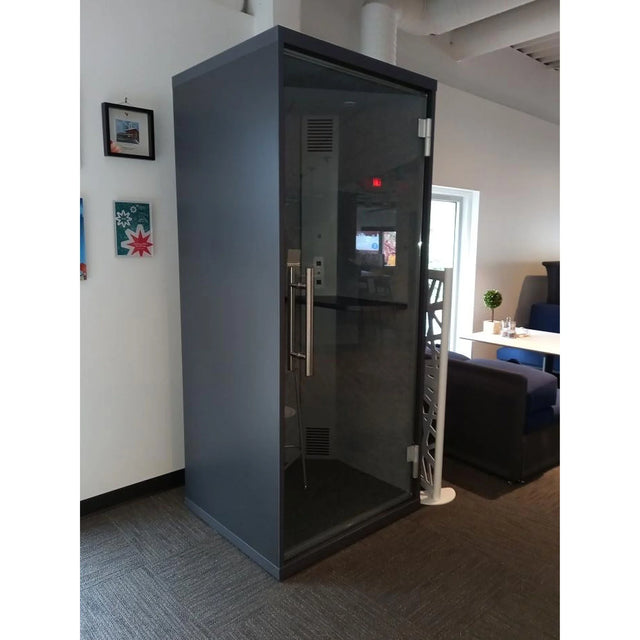 Cabine acoustique OneZone noire installée dans un bureau moderne avec cloison vitrée et éclairage naturel