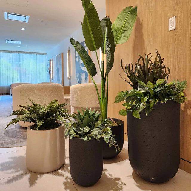Jardinières artificielles ByNature avec plantes réalistes dans un lobby contemporain aux murs de bois clairs