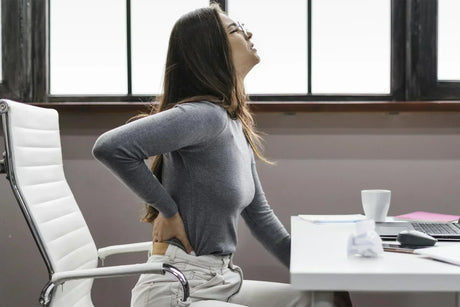 Employé de bureau assis à son poste, avec douleur au dos, posture tendue