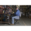 Personne assise sur une chaise Synetik SF180 en vinyle à un établi dans un atelier industriel.