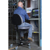Personne utilisant une chaise haute Synetik TF180 en vinyle avec anneau repose-pieds à un poste informatique industriel.